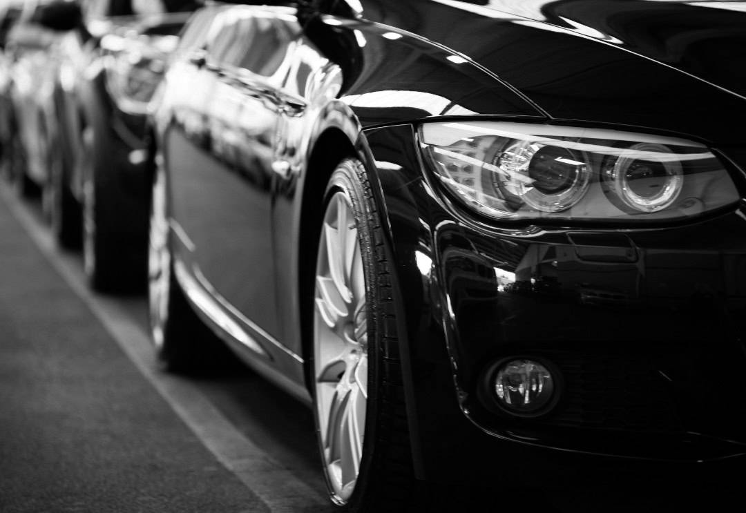 Black car close up of it's side with another black car directly behind it.